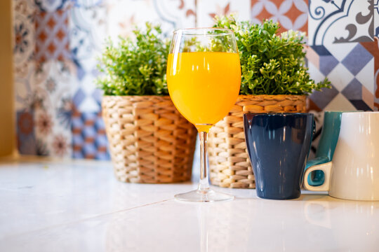 Orange juice in a wine glass is placed on the table in the kitchen.