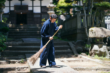 寺の境内を掃除をする日本人の僧侶