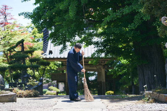 寺の境内を掃除をする日本人の僧侶