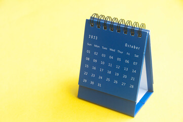October 2023 blue desk calendar on yellow cover background with customizable space for text. Copy space and calendar concept