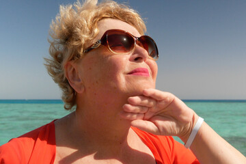 Senior woman wiping the sweat from his forehead with a towel in sea beach, abnormal heat dangerous...