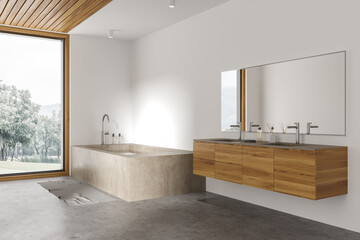 White bathroom corner with massive tub, window and double sink