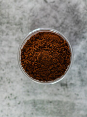 Top view of coffee powder in glass bowl with defocused background.