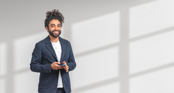 Smiling Middle Eastern businessman holding smartphone, white