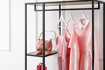Shelving unit with clothes, bag and shoes near light wall