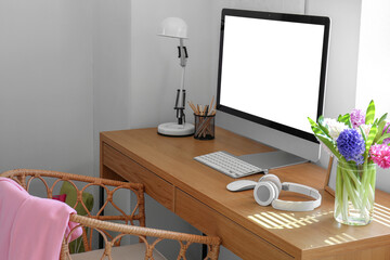 Modern PC, lamp, pencils, beautiful hyacinth flowers and headphones on wooden table in room