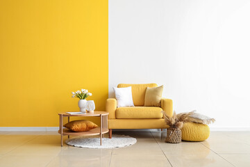 Cozy armchair and coffee table with tulip flowers in vase near colorful wall