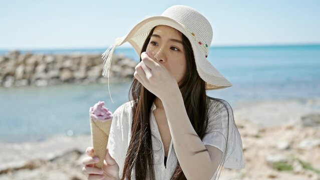 Young chinese woman tourist smiling confident eating ice cream at seaside
