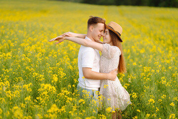 Naklejka na ściany i meble Young Couple in the blooming field. Nature, vacation, love, relax and lifestyle. Summer landscape. 
