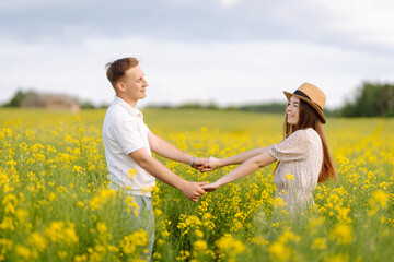 Fototapeta premium Young Couple in the blooming field. Nature, vacation, love, relax and lifestyle. Summer landscape. 