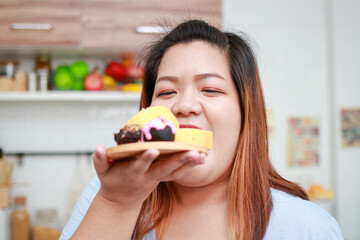 Asian fat woman eating delicious chocolate dessert in hand. Healthy eating concept. Weight loss. Happy woman likes to eat.