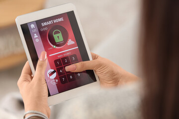 Young woman using smart home security system control panel, closeup