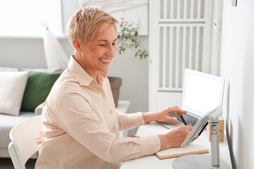 Mature female programmer working with laptop at home