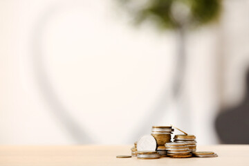 Stacks of coins on wooden table against blurred background