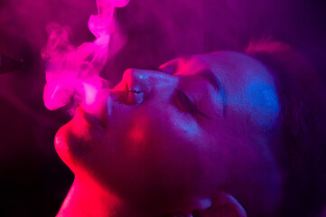 Close up portrait of asian woman with short hair smoking in neon light. 