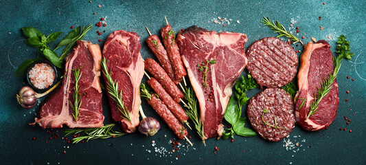 A set of steaks and veal meat. Meat products. On a black stone background. Top view.