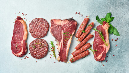 Assortment of meat and meat products. Steak, ribeye steak, kebab and burger patty. On a gray stone background. Top view.
