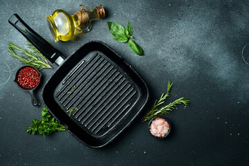 ooking background, free space for text. Grill pan, spices and herbs. On a black stone background. Top view.