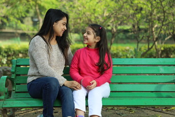 Naklejka premium Happy Indian mother and daughter having a good time in park surrounded with lush green area.