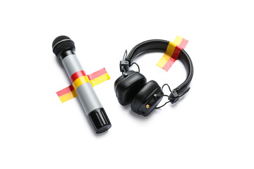 Microphone with headphones and adhesive tapes on white background