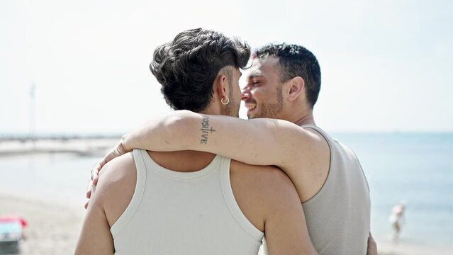 Two men couple hugging each other and kissing backwards at beach
