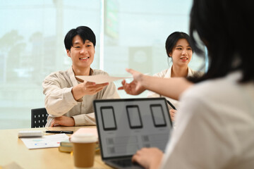 Smiling male UX designer working on sketch designs, application template layout framework with colleagues in office