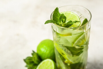 Glass of cold mojito on light background