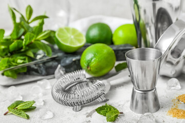 Measure cup and ingredients for preparing mojito on light background
