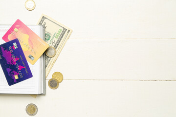 Open notebook with credit cards and money on white wooden table