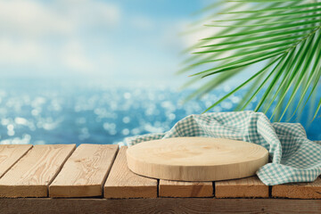 Empty wooden podium with tablecloth on table over tropical beach bokeh background.  Summer mock up for design and product display