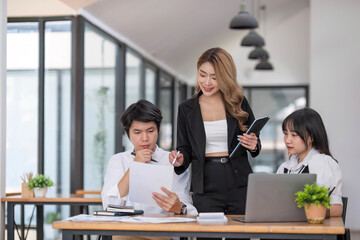 Asian business team consists of marketing staff. accountant and financial officer Help each other analyze company profits using tablets. calculator Laptop computers, graph paper, and corporate pens.