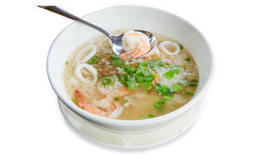 Top view of boiled rice soup with shrimps and squid, focus selective