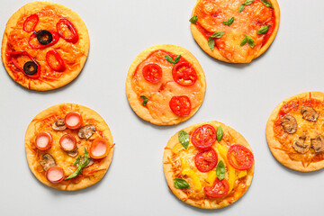 Different tasty mini pizzas on grey background