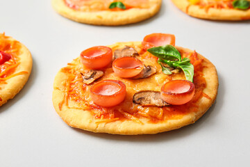 Different tasty mini pizzas on grey background