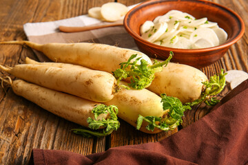 Bowl with slices of fresh daikon radish on wooden background