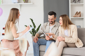 Young couple with wedding planner choosing color palette in office