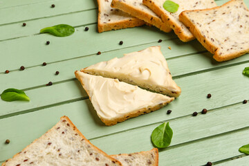 Tasty toasts with cream cheese on green wooden background