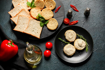 Plate of tasty croutons with cream cheese on dark background