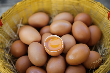 Top view of chicken eggs in basket and broken single egg with yolk. close up of many chicken eggs and yolks in the basket