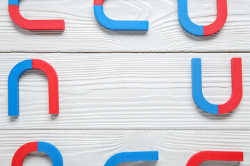 Frame made of magnets on white wooden background