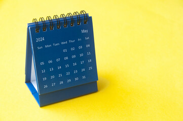 May 2024 blue desk calendar on yellow cover background with customizable space for text. Copy space...