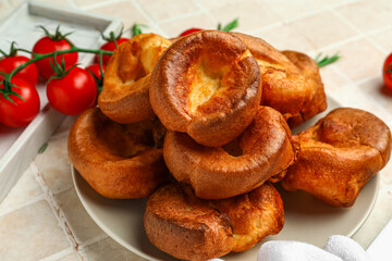 Plate with tasty Yorkshire pudding on light tile background