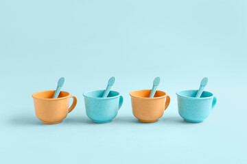 Different colorful cups with spoons on blue background. Children's Day celebration