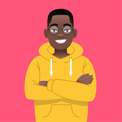 A happy black young guy in glasses stands with his arms crossed. African successful confident boy in yellow hoodie.