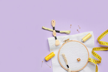 Embroidery hoop with canvas, mouline threads and measuring tape on lilac background