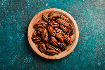 Caramelized pecans in a bowl. Top view. On a dark background.