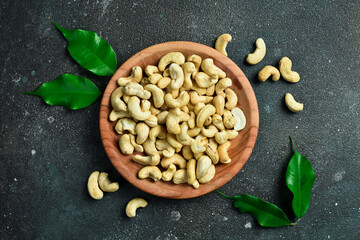 Cashew nut in a wooden bowl. Healthy snacks. On a dark background.
