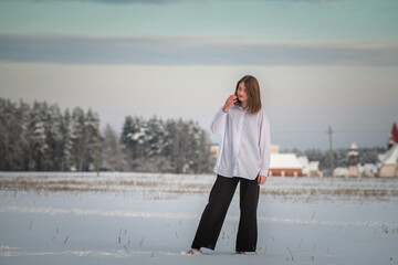 Portrait of a young beautiful girl in the snow in winter outdoors.