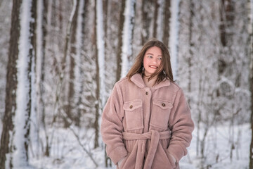 Portrait of a young beautiful girl in the snow in winter outdoors.
