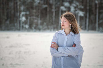Portrait of a young beautiful girl in the snow in winter outdoors.